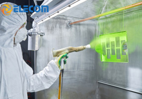 Worker-in-a-protective-suit-sprays-bright-green-powder-coating-material-from-a-spray-gun-onto-a-rectangular-metal-part.jpg